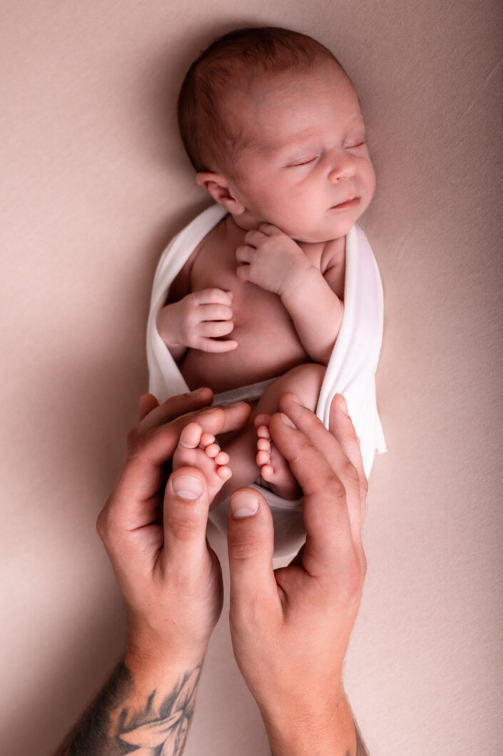 Sesja noworodkowa Olsztyn. Stópki niemowlęce. Stópki córeczki w rękach taty. Malutkie stópeczki.